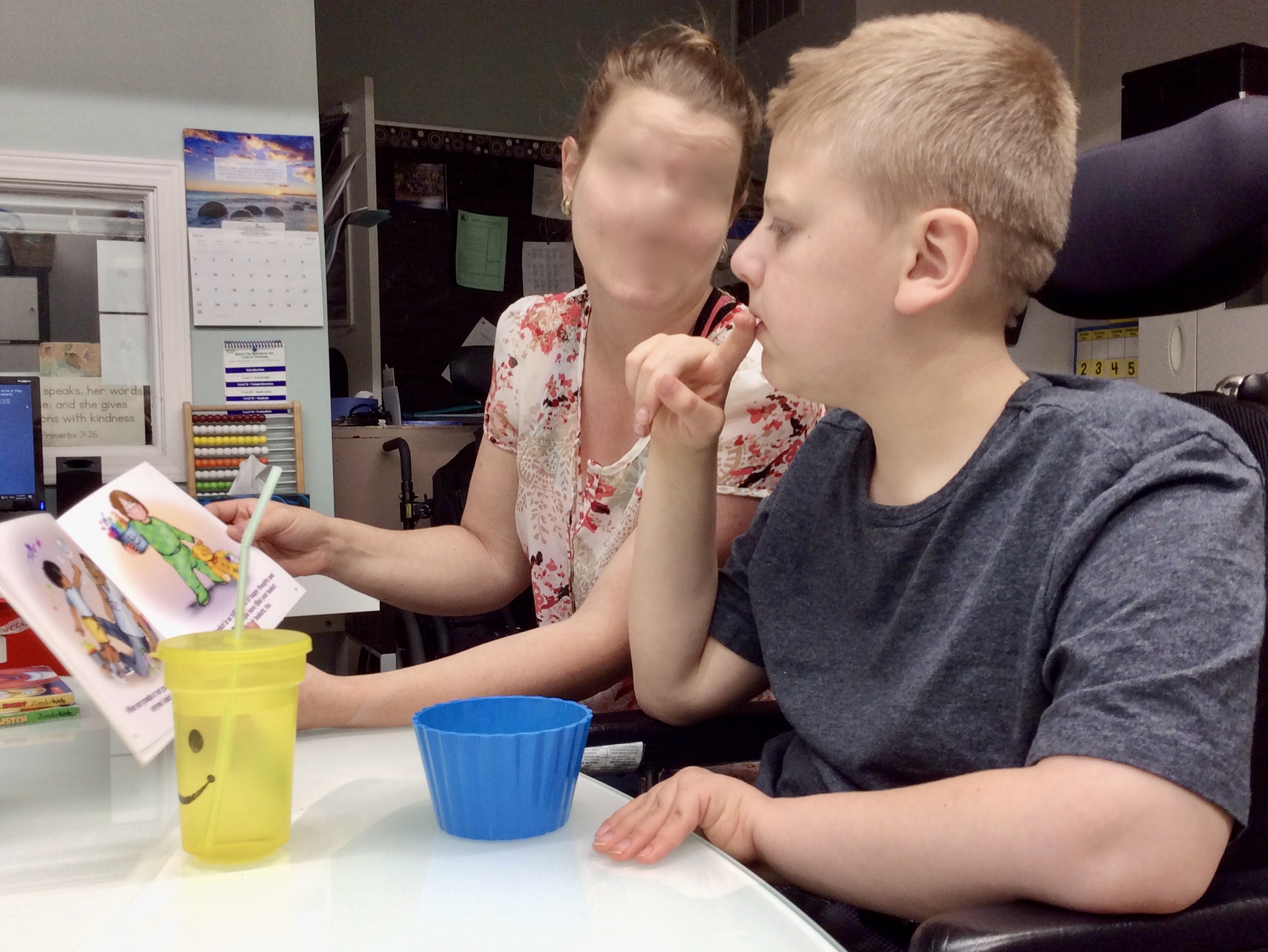 A student with complex needs sits and reads with a peer