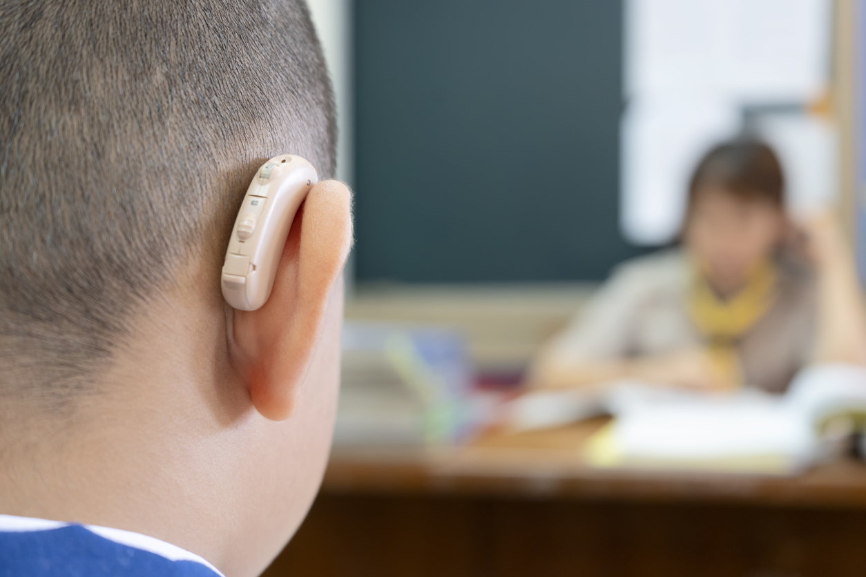 Students who wear hearing aids to increase hearing efficiency. Helps to be able to learn as much as a friend. The background is a teacher who is talking to him